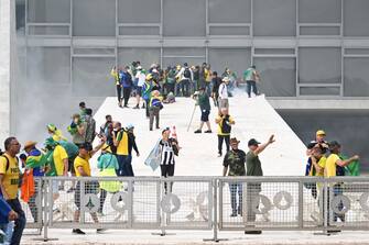 Supporters of Brazilian former President Jair Bolsonaro clash with the police during a demonstration outside Brazil's National Congress headquarters in Brasilia on January 8, 2023. - Brazilian police used tear gas Sunday to repel hundreds of supporters of far-right ex-president Jair Bolsonaro after they stormed onto Congress grounds one week after President Luis Inacio Lula da Silva's inauguration, an AFP photographer witnessed. (Photo by EVARISTO SA / AFP) (Photo by EVARISTO SA/AFP via Getty Images)