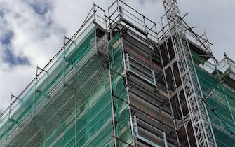 Works for adaptation and energy saving of houses in Italy. Low angle view of a tall building with scaffolding in front of the facades.