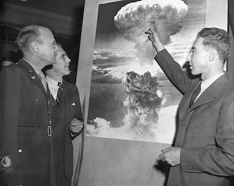 Three of the men who played leading roles in the development of the atomic bomb visit the American Chemical Society Atomic Exhibit in Grand Central Palace. Looking at a photo of the atomic explosion over Nagasaki, Japan, are left to right, Brig. Gen. K. D. Nichols, Prof. H.D. Smythe who wrote the government atomic report and J.R. Oppenheimer, director of the Los Alamos, N.M. atomic labratory.