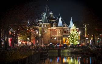 Amsterdam Christmas tree at the Waag building on the Newmarkt square with Christmas lights illuminating the pine tree in the evening.