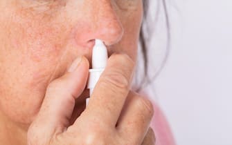 Close up of woman hands using nasal spray.