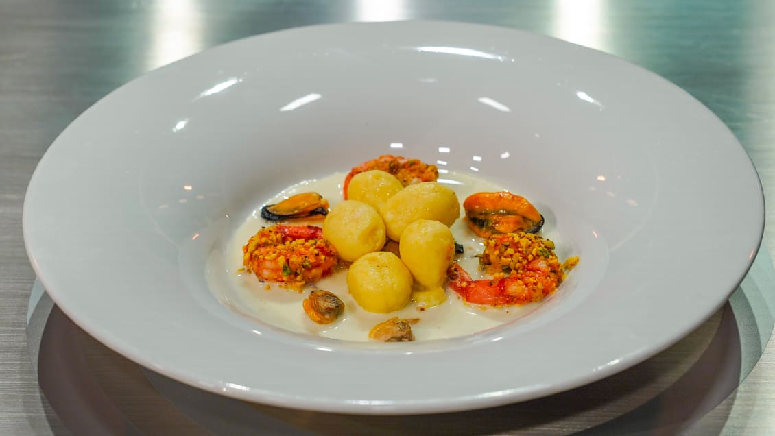 Gnocchi di patate e caciocavallo su crema di sedano rapa con cozze, vongole e gamberoni croccanti