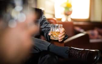 Close-up shot of a businessman hand holding a glass of whiskey