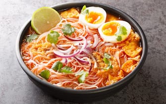 zuppe Burmese Mohinga Rice Noodle Fish Soup closeup in the bowl on the table. Horizontal