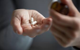 Young woman taking prescribed antibiotic pills or vitamins