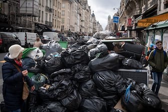 Pedestrians walk past waste that has been piling up on the pavement as waste collectors are on strike since March 6 against the French government's proposed pensions reform, in Paris on March 13, 2023. (Photo by ALAIN JOCARD / AFP) (Photo by ALAIN JOCARD/AFP via Getty Images)