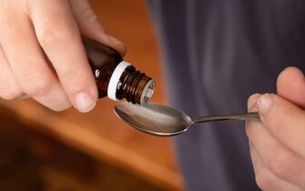 take medicine from a spoon,drip cough syrup closeup.