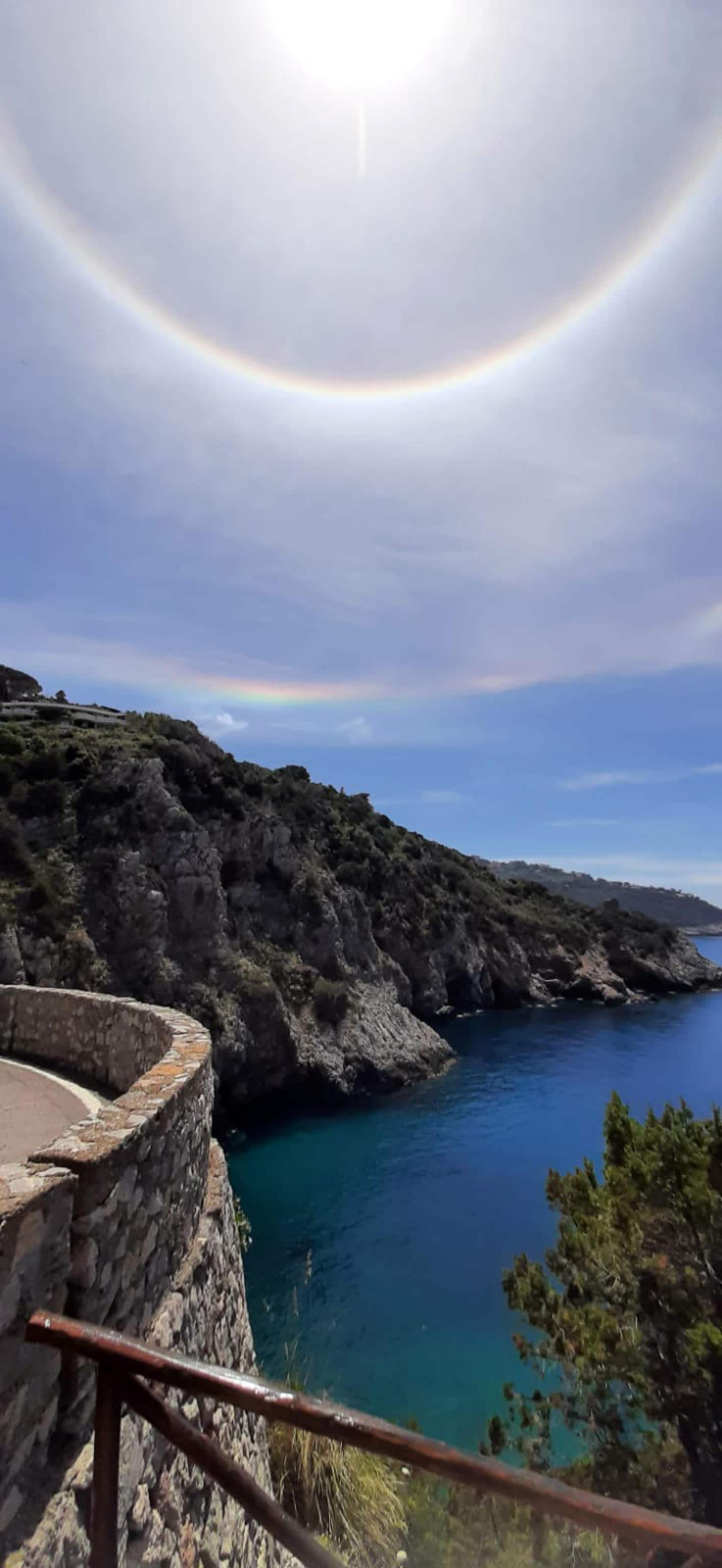 L aura solare, un raro fenomeno meteo, visto all'Argentario, 29 maggio 2021. L'alone e l'arcobaleno circolare attorno al Sole è un evento raro (ma naturale) ed è un fenomeno simile all'arcobaleno eccetto per il fatto che viene formato dalla rifrazione della luce solare attraverso i cristalli di ghiaccio sospesi nelle nuvole al posto delle gocce di pioggia o ad altra acqua liquida sospesa nel cielo. 
ANSA/Bonaccorso Maria Emilia