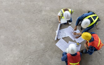 Top view of engineer, architect, contractor and foreman meeting at the construction building site with floor plan for real estate development project industry and housing timeline usage