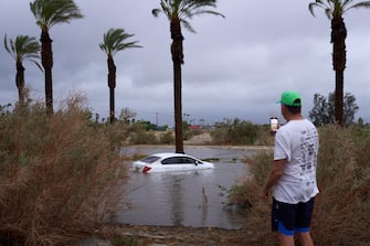 epa10811214 A person takes a photo of a car submerged in flooded water as Tropical Storm Hilary arrives in Cathedral City, California, USA, 20 August 2023. Southern California is under a tropical storm warning for the first time in history as Hilary makes landfall. The last time a tropical storm made landfall in Southern California was 15 September 1939, according to the National Weather Service.  EPA/ALLISON DINNER