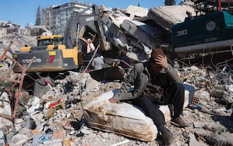 A man sits on ruins in Kahramanmaras, Turkey, Wednesday, February 8, 2023. On February 6, a 7.8-magnitude shook Turkey and Syria, followed a few hours later by 7.5-magnitude earthquake. The death toll rises to 11600 in Turkey and Syria. (Photo by Arnaud Andrieu/Sipa Press).
