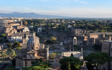 At sunset, the sun illuminates the Imperial Forums and the Church of Santi Luca e Martina with golden rays. The panorama is seen from the top of the terrace of the Altare della Patria.