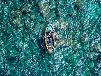 CATANIA, ITALY - AUGUST 15: Aerial view of a small boat in the sea of the Catanese cliffs on August 15, 2022 in Catania, Italy. 15 August is traditionally spent at the seaside in Sicily by thousands of families. This year, the island, especially the east coast of Sicily, was visited by thousands of tourists who sold out restaurants and hotels. (Photo by Fabrizio Villa/Getty Images)