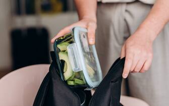 woman makes a healthy lunch at the lunch box zucchini pancakes and avocado salad , healthy lunch to go for school and college students