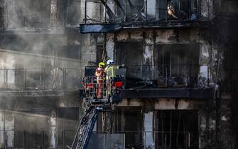 epa11174193 Firefighters check the facade of a building after a fire, in Valencia, Spain, 23 February 2024. A fire broke out in a residential building in Valencia on the afternoon of February 22, and spread to an adjacent condominium, leaving four dead and 19 missing.  EPA/Biel Alino