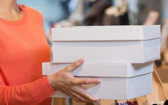 woman or shop assistant with shoe boxes at store