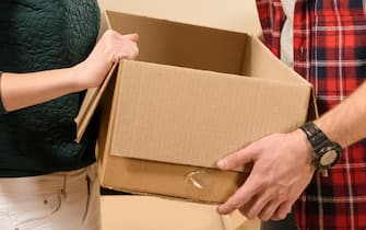side view of young smiling couple looking into cardboard box at new home