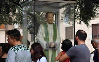 People gather by a statue of late priest Pino Puglisi, outside the house museum and "Padre Nostro" welcome center in the Brancaccio district of Palermo, Sicily, on September 14, 2018 on the eve of the Pope's visit to the Diocese. - Pope Francis is to pay a one-day pastoral visit on September 15 the Dioceses of Piazza Armerina and Palermo in Sicily, on the occasion of the 25th anniversary of the killing by the mafia of Sicilian priest Pino Puglisi. (Photo by Andreas SOLARO / AFP) (Photo by ANDREAS SOLARO/AFP via Getty Images)
