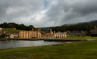 Tasmania, Australia-02 August 2018: The old sandstone buildings of the historical convict prison at Port Arthur, Tasmania surrounded by greenery and visited on a dark and heavily clouded day.