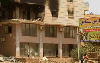 Two men walk past a building damaged during battles between the forces of two rival Sudanese generals in the southern part of Khartoum, on April 23, 2023. - Hundreds of people have been killed and thousands wounded since the fighting erupted on April 15 between forces loyal to the Sudanese army chief and his deputy who commands the powerful paramilitary Rapid Support Forces (RSF). (Photo by AFP)