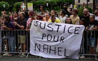 Spectator deploy a banner which reads "Justice for Nahel" along the race route at the start of the 1st stage of the 110th edition of the Tour de France cycling race, 182 km departing and finishing in Bilbao, in northern Spain, on July 1, 2023. Clashes continued across France despite the 45,000 police officers deployed, the highest number of any night since the start of the protests, backed by light armoured vehicles and elite police units. Police made more than 1,000 arrests and the country braced for more riots ahead of the funeral of the 17-year-old teenager who was killed by a police officer during a traffic stop. (Photo by Marco BERTORELLO / AFP)