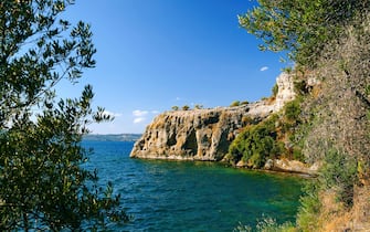 Jagged coast and blue sky in summer on Bisentina Island, one of the two islands of the Bolsena Lake, a crater lake of volcanic origin