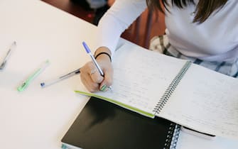 A view of a high school student taking notes in her notepad during class.