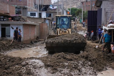 A tractor helps resident of the semi-rural district of La Esperanza, north of Trujillo in La Libertad Department, Peru, to removes mud and sand from the street and the front of their houses on March 13, 2023, after heavy rains caused by Cyclone Yaku. - At least 59 dead and more than 12,000 homeless have left the rainy season in Peru since September due to floods and overflowing rivers, the Civil Defence reported on March 12. The floods accompanied by strong winds that affect part of Peru increased in the last 72 hours and affected urban and rural areas of the coastal departments of Ancash, La Libertad, Lambayeque, Piura and Tumbes, near the border with Ecuador. (Photo by Arturo GUTARRA / AFP) (Photo by ARTURO GUTARRA/AFP via Getty Images)