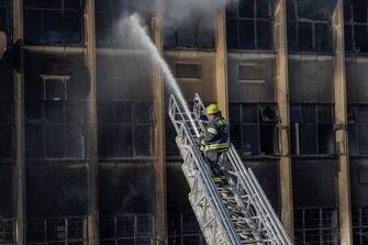 EDITORS NOTE: Graphic content / A firefighter extinguishes the fire at a building in Johannesburg on August 31, 2023. At least 20 people have died and more than 40 were injured in a fire that engulfed a five-storey building in central Johannesburg on August 31, 2023, the South African city's emergency services said. (Photo by Michele Spatari / AFP) (Photo by MICHELE SPATARI/AFP via Getty Images)