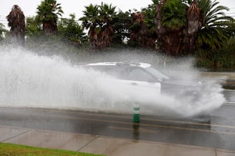 epa10811132 A car drives through standing water on a road in Long Beach, California, USA, 20 August 2023. Southern California is under a tropical storm warning for the first time in history as Hilary makes landfall. The last time a tropical storm made landfall in Southern California was 15 September 1939, according to the National Weather Service.  EPA/CAROLINE BREHMAN