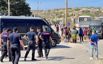 Migranti in attesa di essere caricati sugli autobus per raggiungere il porto dove verranno imbarcati su navi militari e traghetti di linea, Lampedusa, 14 settembre 2023. ANSA/ELIO DESIDERIO