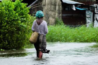 epa10515411 A women walks on a flooded street near Quelimane, as the storm Freddy hits in Quelimane, Mozambique, 11 March 2023. The provincial capital of Quelimane will be the largest urban area closest to the cyclone's point of arrival on the mainland, and its radius (of about 300 kilometres) is expected to extend from Marromeu to Pebane, then moving inland towards Cherimane and southern Malawi. This is one of the longest lasting storms ever, after it formed at the beginning of February in the Asian seas, crossing the entire Indian Ocean to the east African coast.  EPA/ANDRÉ CATUEIRA