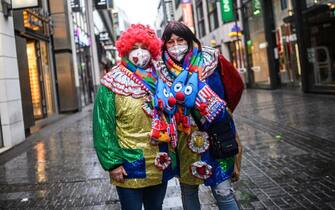 COLOGNE, GERMANY - FEBRUARY 15: A lone pair of carnival enthusiasts walk past shuttered shops in the city center on Rose Monday, the day that is normally the height of Germany's carnival season, during the second wave of the coronavirus pandemic on February 15, 2021 in Cologne, Germany. Carnival celebrations have been cancelled nationwide this year as part of ongoing lockdown measures. (Photo by Lukas Schulze/Getty Images)