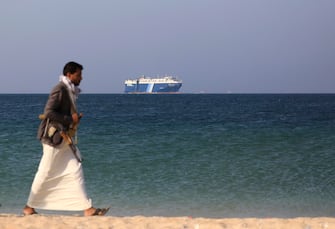 epaselect epa11014295 An armed Houthi fighter walks through the beach with the Galaxy Leader cargo ship in the background, seized by the Houthis offshore of the Al-Salif port on the Red Sea in the province of Hodeidah, Yemen, 05 December 2023 (issued 06 December 2023). Yemen's Houthis on 06 December 2023 claimed responsibility for the launch of the barrage of ballistic missiles toward Israel in support of the Palestinian people in the Gaza Strip, according to a statement by Houthis spokesman Yahya Saree. The Houthis vowed to continue their efforts to prevent Israeli ships from navigating in the Arabian and Red Seas, in retaliation for Israel's airstrikes on the Gaza Strip. Thousands of Israelis and Palestinians have died since the militant group Hamas launched an unprecedented attack on Israel from the Gaza Strip on 07 October, and the Israeli strikes on the Palestinian enclave which followed it.  EPA/YAHYA ARHAB