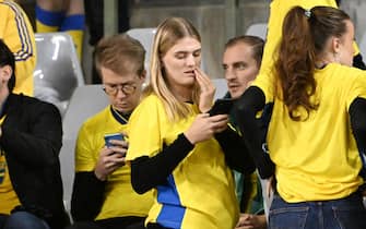 BRUSSELS, BELGIUM - OCTOBER 16: A concerned Sweden checks her phone in the stands at half-time as the UEFA EURO 2024 European qualifier match between Belgium and Sweden is postponed at King Baudouin Stadium on October 16, 2023 in Brussels, Belgium. The match was postponed after an 'attack' that killed two Swedish citizens in a street of Brussels, Belgium. (Photo by Isosport/MB Media/Getty Images)
