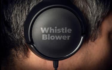 Whistleblower concept: a mystery man wear a pair of headphone with the  engraved text: wistle blower