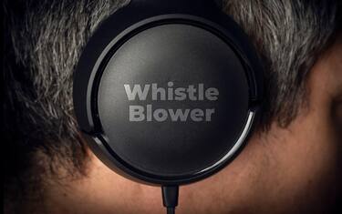 Whistleblower concept: a mystery man wear a pair of headphone with the  engraved text: wistle blower