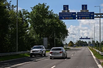 PAGEGIAI, LITHUANIA - JULY 10: A car drives past a traffic sign saying Kaliningrad Oblast, a semi-exclave situated from on the Baltic Sea bordering the Lithuanian town Pagegiai on July 10, 2023 in Pagegiai, Lithuania. The Queen Louise Bridge connects Pagegiai to the Russian exclave Kaliningrad. The car traffic remains closed and just pedestrians are authorized to commute by the bridge. On one of the buildings by the riverside, the Letter Z, a symbol of the Russian war on Ukraine is painted facing the Lithuanian town. By the Lithuanian- Belarusian border, next to the town, Dieveniskes, the Lithuanian border guard continues to patrol by the border wall, as Belarus authorities weaponized migration for the past 2 years. (Photo by Omar Marques/Anadolu Agency via Getty Images)