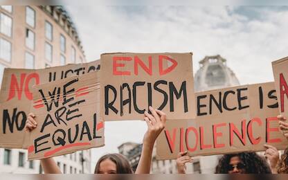 People are marching on strike against racism in the city. They are holding cardboard signs.