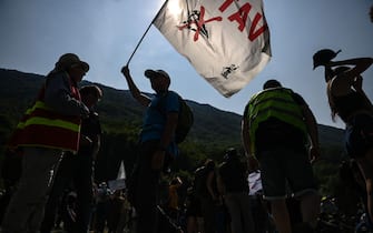 Protesters are seen in silhouette as they take part in a demonstration against the construction of a high-speed rail line between Lyon and Torino, in La Chapelle, near Modane, in the French Alps' Maurienne valley, on June 17, 2023. Hundreds of oponents to the Lyon-Torino high-speed rail line demonstrated on June 17 despite a ban on the gathering, of which the details are yet to be determined and despite a heavy police presence in the valley. They set up a makeshift camp on land lent by the municipality of La Chapelle, outside the ban zone announced the day before by the Savoie prefecture. (Photo by OLIVIER CHASSIGNOLE / AFP) (Photo by OLIVIER CHASSIGNOLE/AFP via Getty Images)