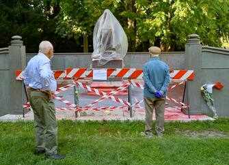 Statua Indro Montanelli transennata e coperta in attesa di pulizia, cittadini portano fiori e biglietti, Polizia Locale in presidio