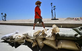 A man walks past sand bags placed to protect beach front homes in Seal Beach, California on August 18, 2023, as they prepare for hurricane Hilary. Hilary strengthened into a Category 4 hurricane on August 18, 2023 and was expected to further intensify before approaching Mexico's Baja California peninsula over the weekend, the US National Hurricane Center (NHC) said. In the US, parts of southern California and southern Nevada could see heavy rain through early next week, the NHC said. (Photo by Frederic J. BROWN / AFP) (Photo by FREDERIC J. BROWN/AFP via Getty Images)