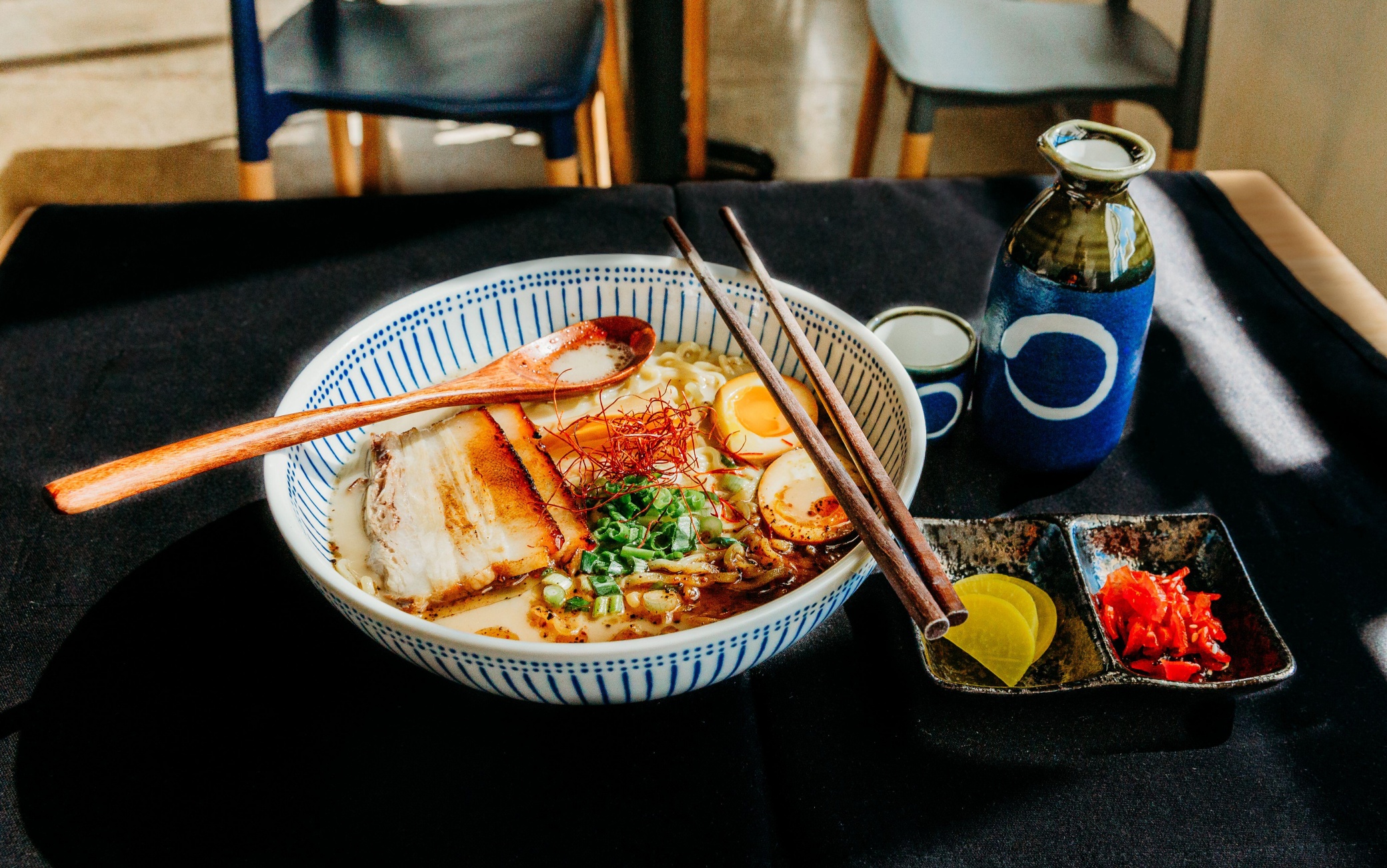 Bowl of tonkatsu ramen on table with wooden spoon in bowl