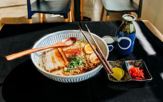 zuppe Bowl of tonkatsu ramen on table with wooden spoon in bowl