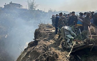 Rescuers and onlookers gather at the site of a plane crash in Pokhara on January 15, 2023. - An aircraft with 72 people on board crashed in Nepal on January 15, Yeti Airlines and a local official said. (Photo by Krishna Mani BARAL / AFP) (Photo by KRISHNA MANI BARAL/AFP via Getty Images)