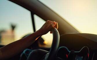 Close-up of female driver holding steering wheel in a car. Car rental. Car insurance.