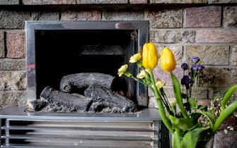 A flower arrangement of tulips beside a switched off home electrical fireplace, within a brick hearth.
