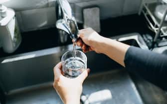 Cropped shot of woman's hand filling a glass of filtered water right from the tap in the kitchen sink at home