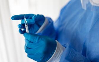 Close-up of a doctor hand wearing protective gloves preparing coronavirus vaccine syringe. Healthcare worker with a vaccination injection.