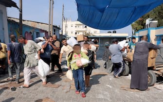 TOPSHOT - Palestinians storm a UN-run aid supply center, that distributes food to displaced families following Israel's call for more than one million residents in northern Gaza to move south for their safety, in Deir al-Balah on October 28, 2023, amid the ongoing battles between Israel and the Palestinian group Hamas. Thousands of civilians, both Palestinians and Israelis, have died since October 7, 2023, after Palestinian Hamas militants based in the Gaza Strip entered southern Israel in an unprecedented attack triggering a war declared by Israel on Hamas with retaliatory bombings on Gaza. (Photo by MOHAMMED ABED / AFP) / "The erroneous mention[s] appearing in the metadata of this photo by MOHAMMED ABED has been modified in AFP systems in the following manner: [Storm] instead of [Collect boxes and and bags from]. Please immediately remove the erroneous mention[s] from all your online services and delete it (them) from your servers. If you have been authorized by AFP to distribute it (them) to third parties, please ensure that the same actions are carried out by them. Failure to promptly comply with these instructions will entail liability on your part for any continued or post notification usage. Therefore we thank you very much for all your attention and prompt action. We are sorry for the inconvenience this notification may cause and remain at your disposal for any further information you may require." (Photo by MOHAMMED ABED/AFP via Getty Images)